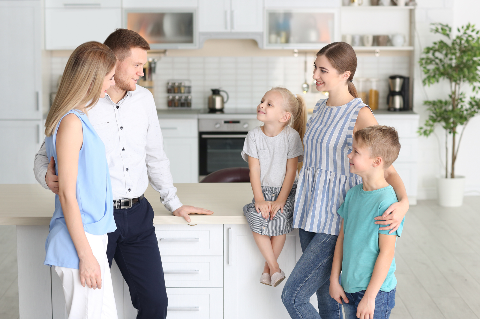 A family with two children and a nanny gathering together in the kitchen.