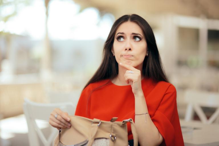 Woman in a red shirt opening her purse pondering how to pay.